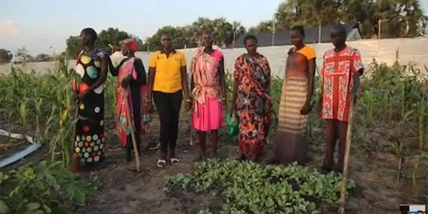 Group standing with hoes in front of garden